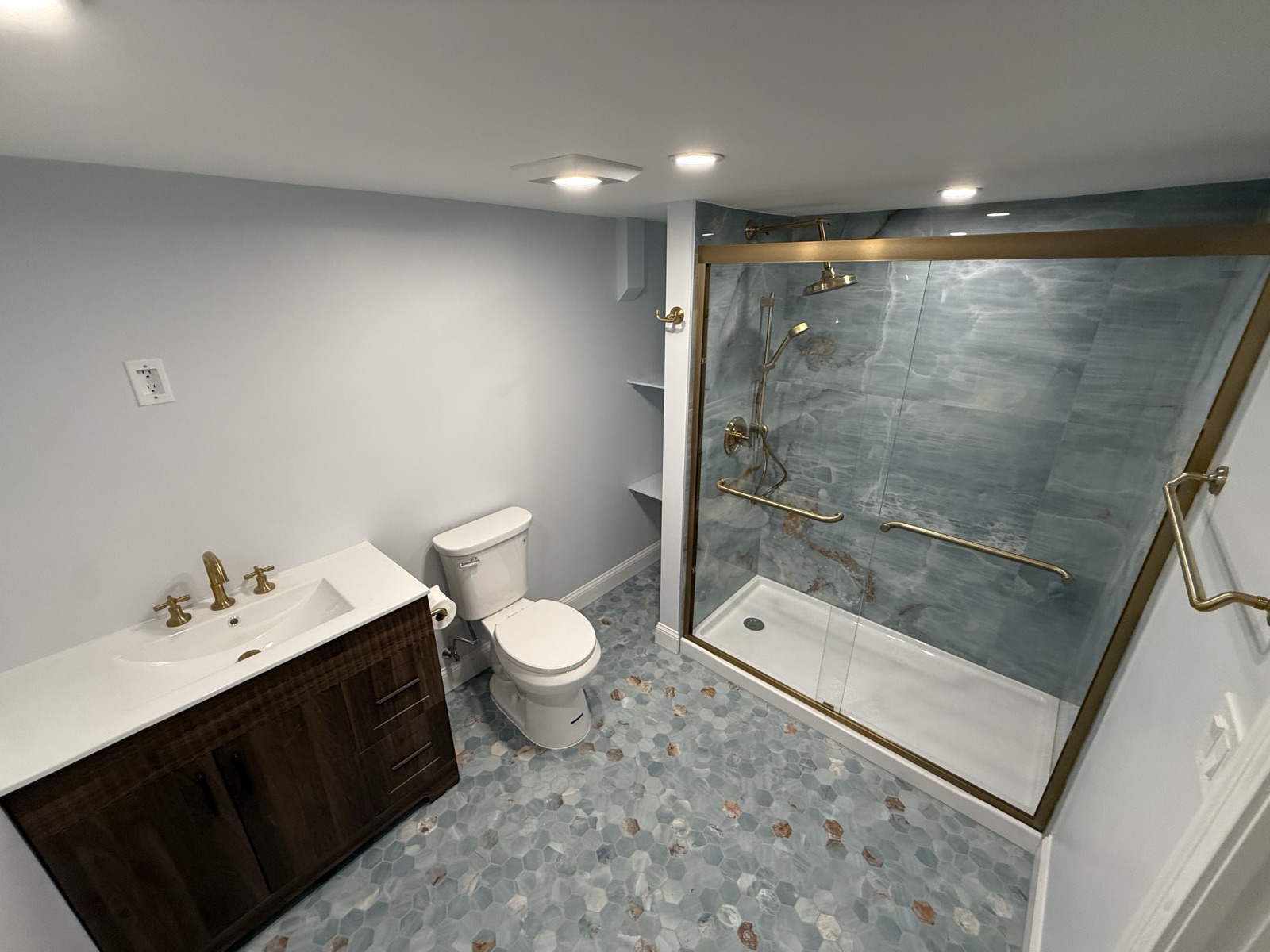 Finished basement bathroom with a walk-in glass shower, a vanity, and a toilet